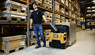 Worker pulling Cat power pallet truck with pallets on it